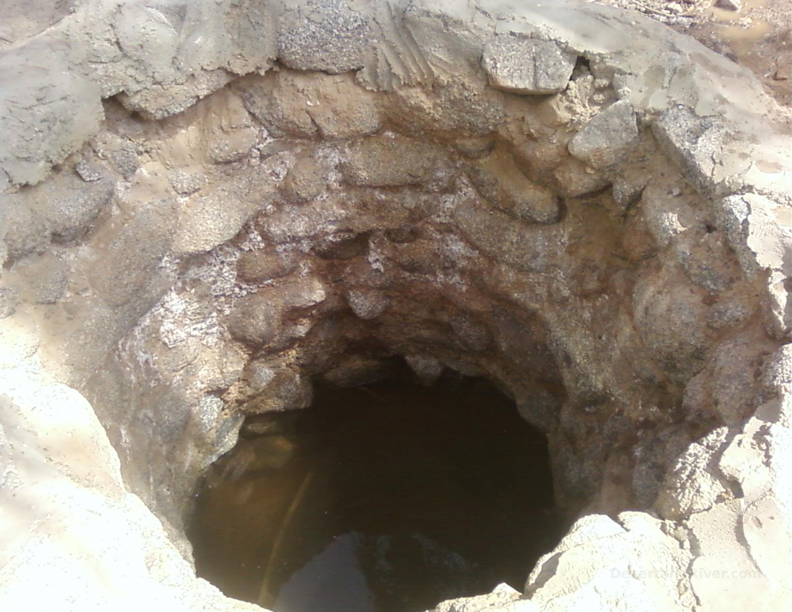 Stone-lined desert well at Bir el Sorah in Wadi Watir, South Sinai, with still water visible at the bottom of the shaft.