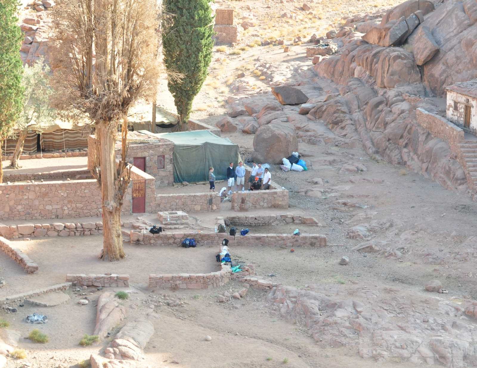 Farsh Eliyah plateau on Mount Sinai, a small resting camp with stone walls and tents set among rocky slopes and desert trees.