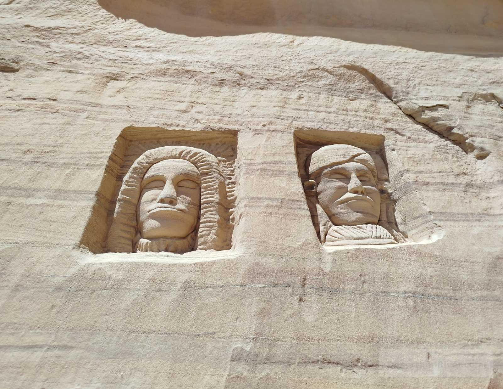 Narrow sandstone passage in the Hidden Canyon near Taba, Sinai Peninsula, with layered rock walls and faint carved inscriptions.