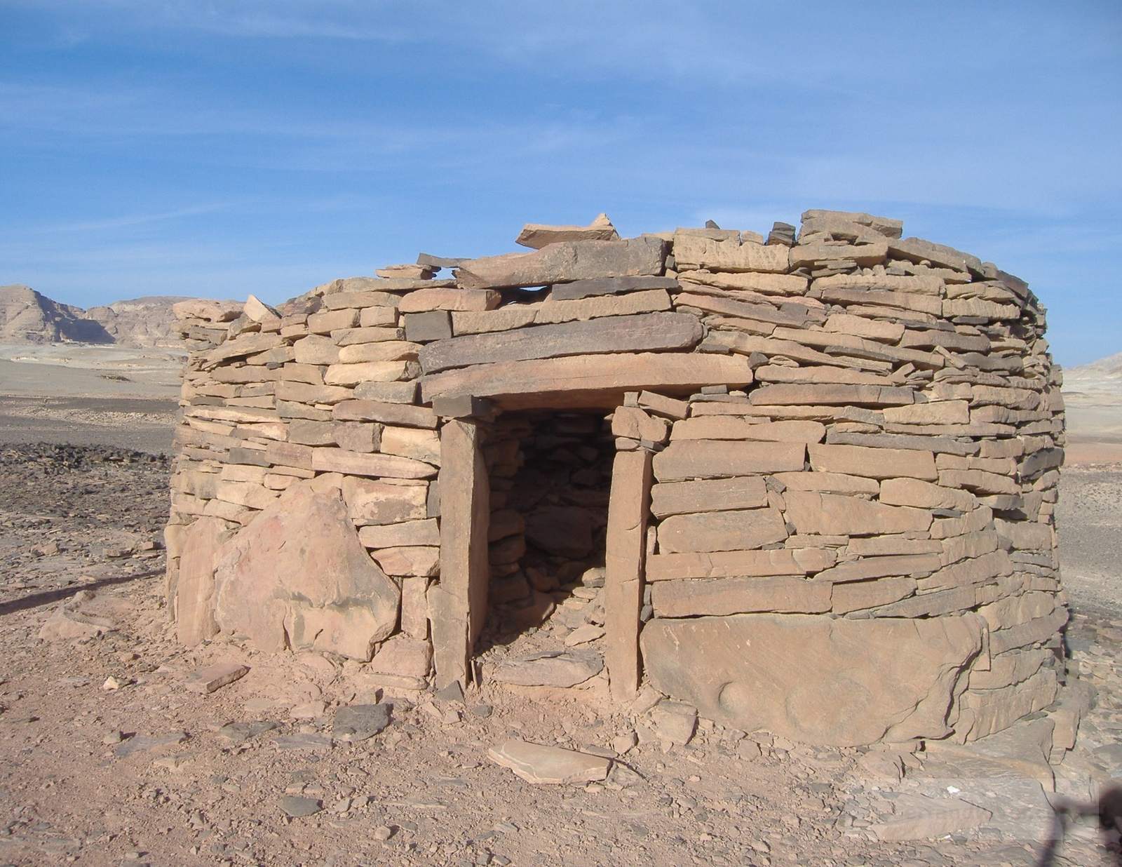 Circular dry-stone Nawamis structure in South Sinai, an early Bronze Age stone chamber on a desert plateau under a clear sky.