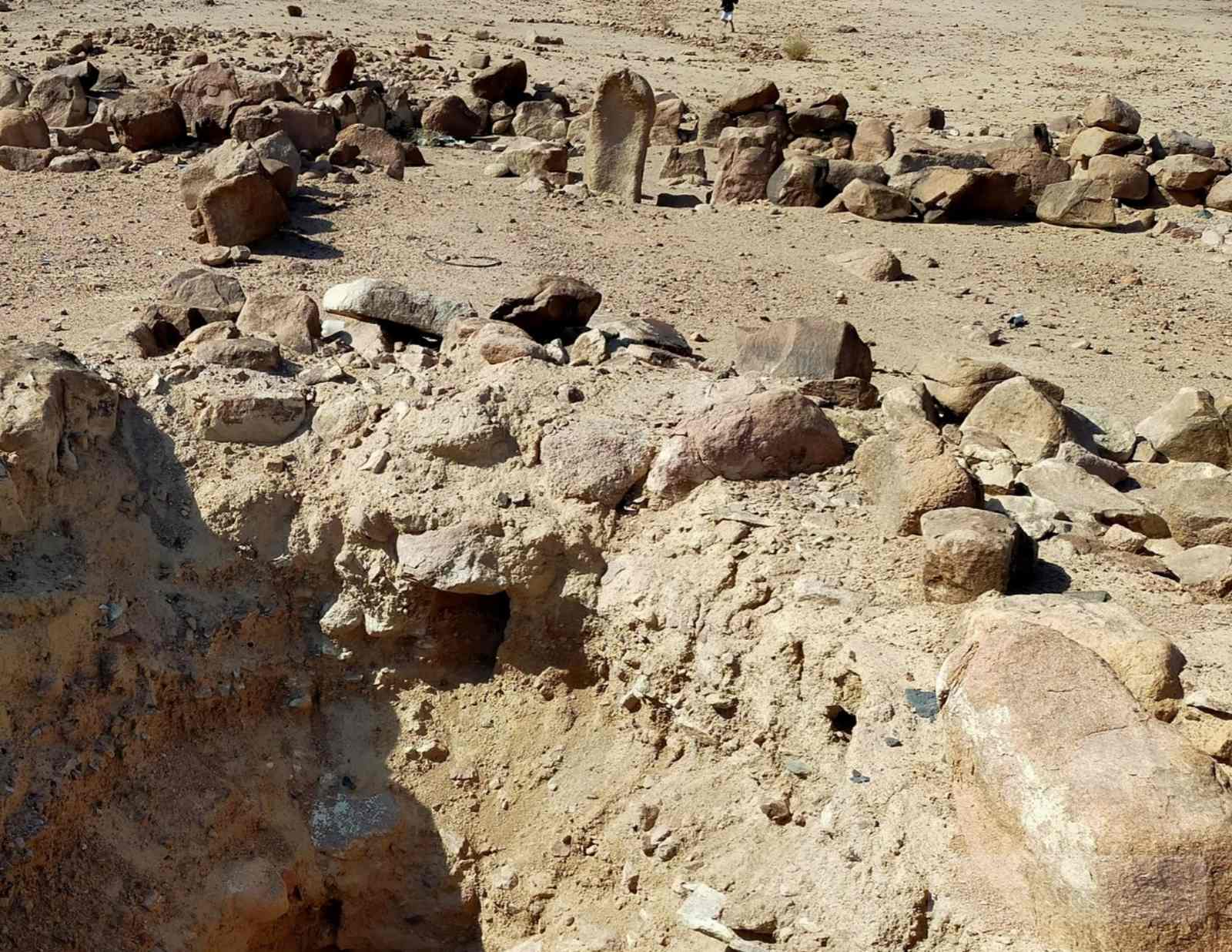 Stone arrangements and desert outcrop at Sheikh Mohsin in South Sinai, with scattered boulders and a wide sandy plain below the hills.