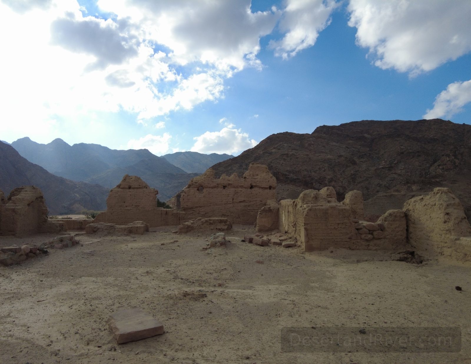 Ruins and sandy terraces in Wadi Feiran, South Sinai, with mountains behind under a bright sky.